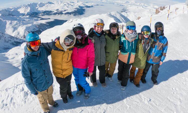 Gruppe junger Leute in Snowboardkleidung in den Bergen