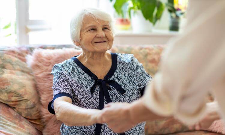 Haushelferin reicht Seniorin die Hände (©iStock-Photo, Halfpoint)